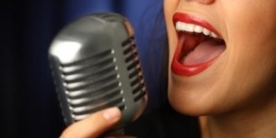 mujer cantando con microfono vintage durante la clase de canto en Natural voice sevilla